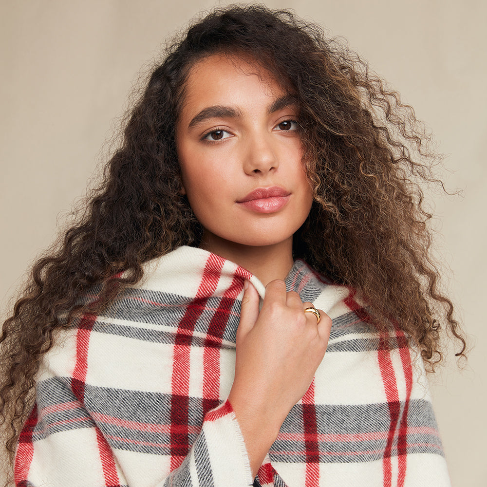 Woman wearing a plaid shawl against a neutral background