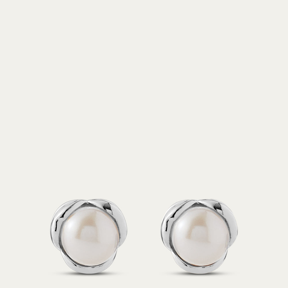 Pair of silver earrings with pearls on a light gray background