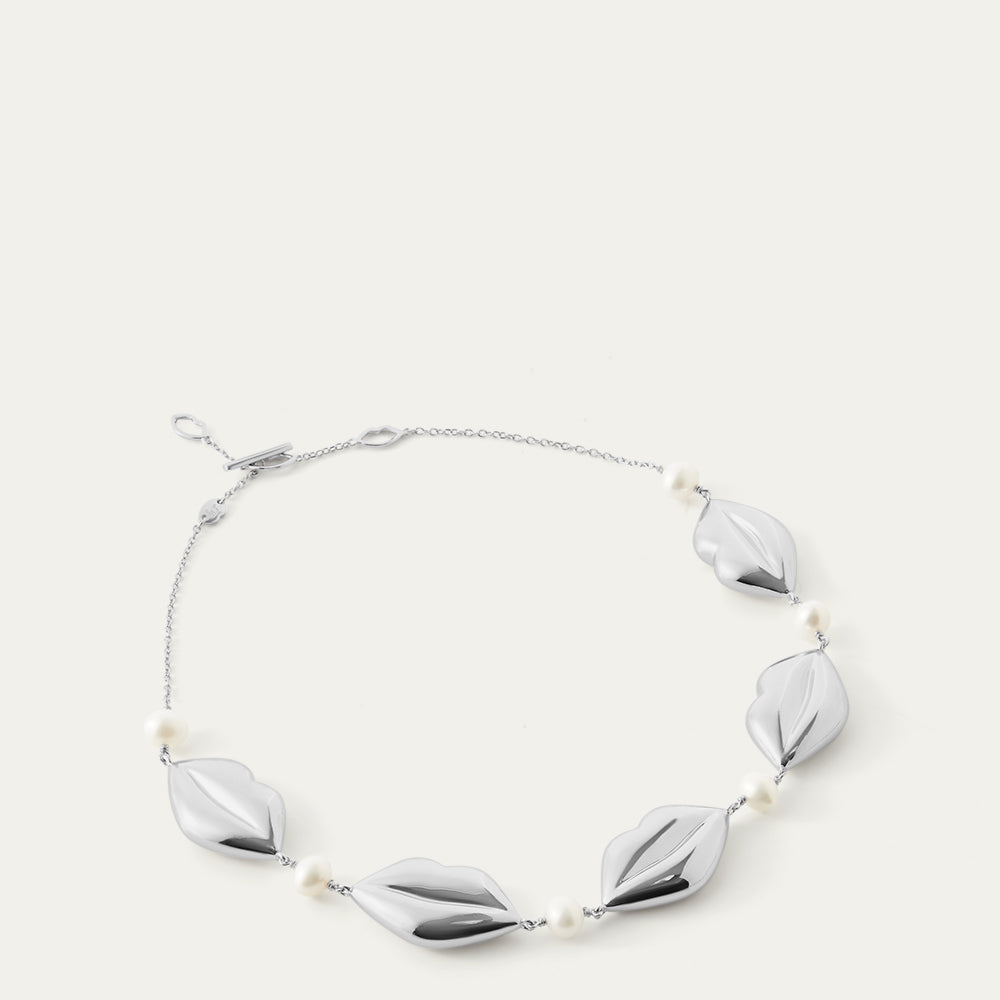 Silver necklace with lip-shaped pendants and pearls on a white background