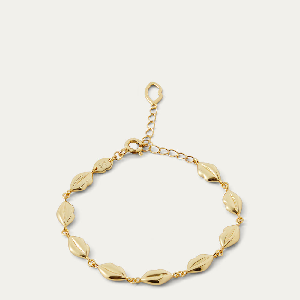 Gold bracelet with lip-shaped links on a light gray background