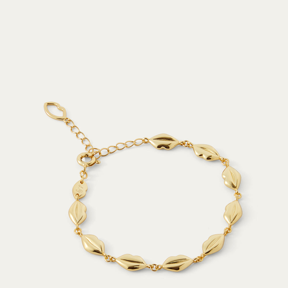 Gold bracelet with lip-shaped links on a light beige background