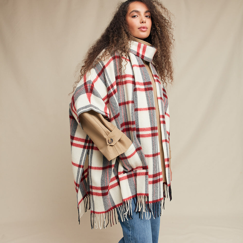 Woman wearing a plaid jacket over a beige jacket on a beige background