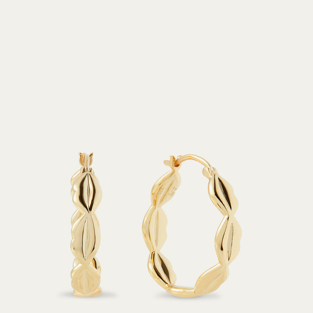 Gold hoop earrings on a light beige background