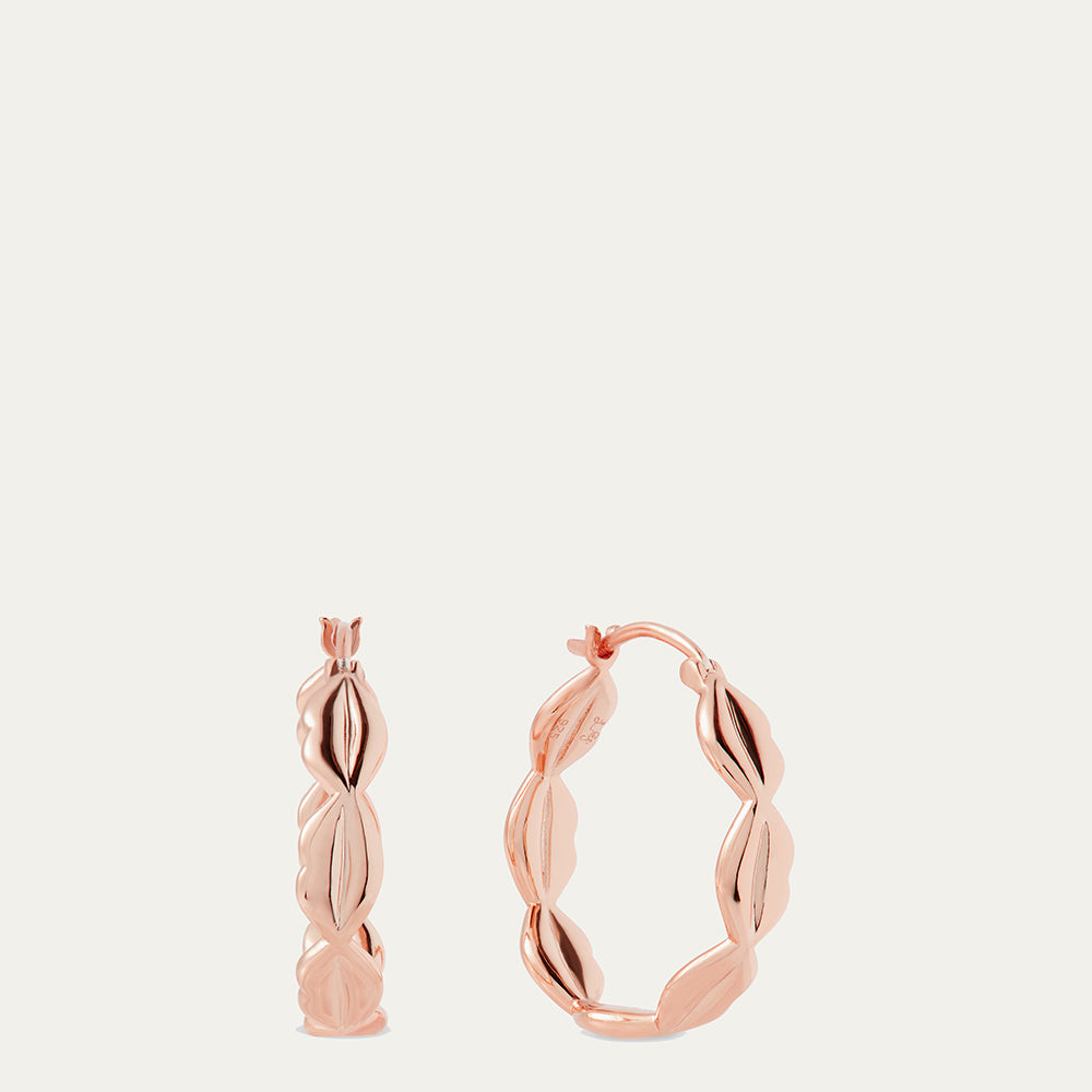 Rose gold hoop earrings on a light beige background