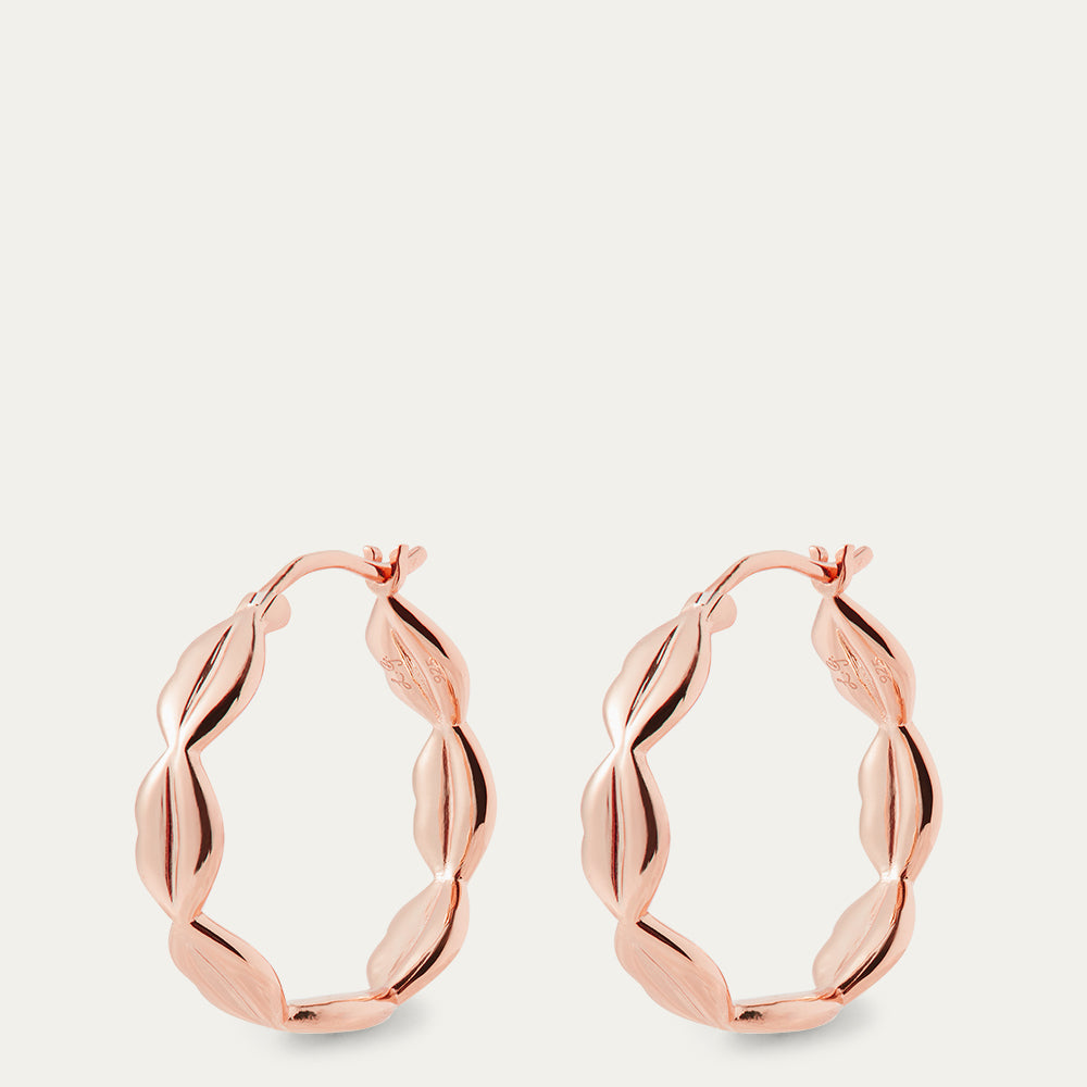 Rose gold hoop earrings on a light beige background