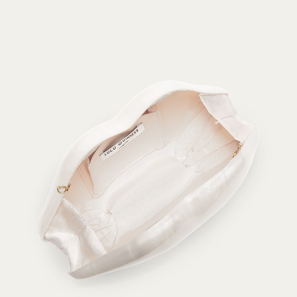 White lip shaped clutch open to reveal a ivory lining on a white background