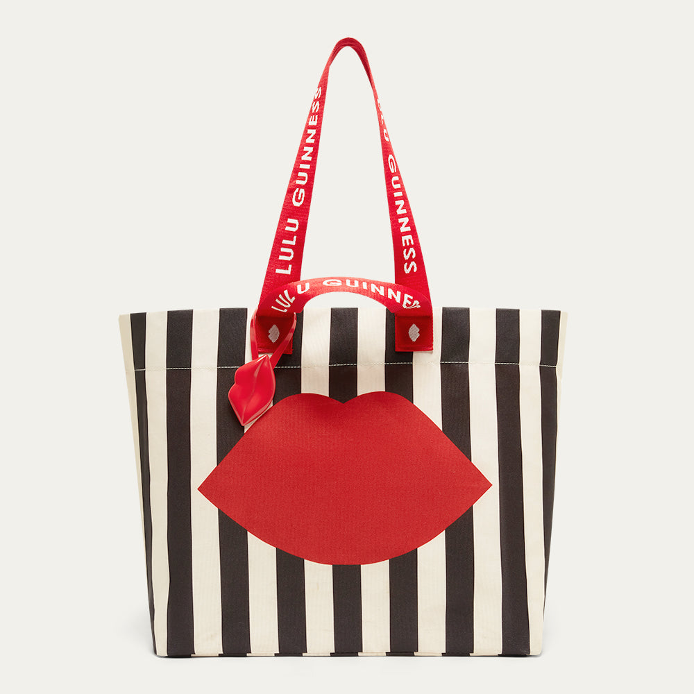 Black and Beige striped tote bag with red lips design and red branded 'Lulu Guinness' handle on a light gray background