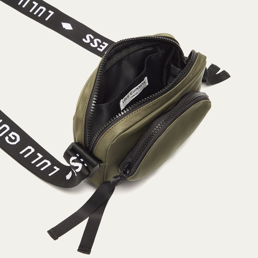 Green crossbody bag with black 'Lulu Guinness' strap open on a white background