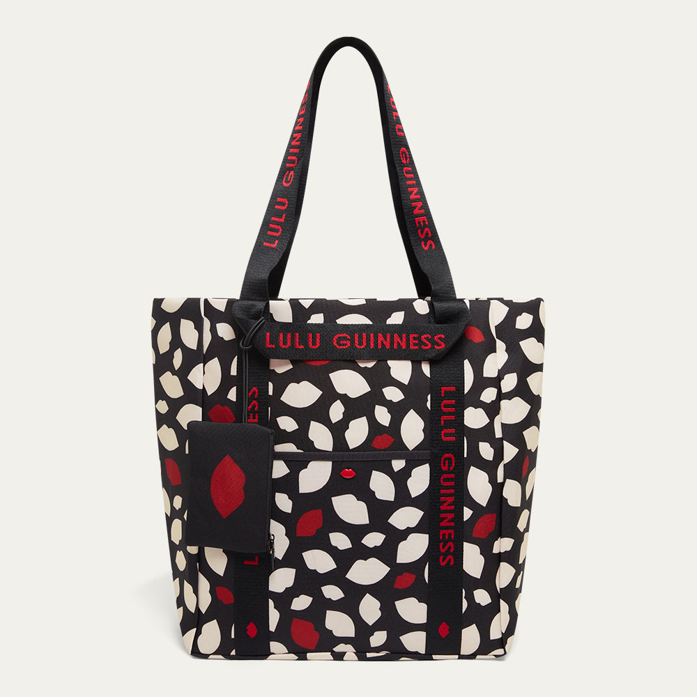 Tote bag with red and white lip flurry print and 'Lulu Guinness' branding with a detachable lip print pouch on a white background