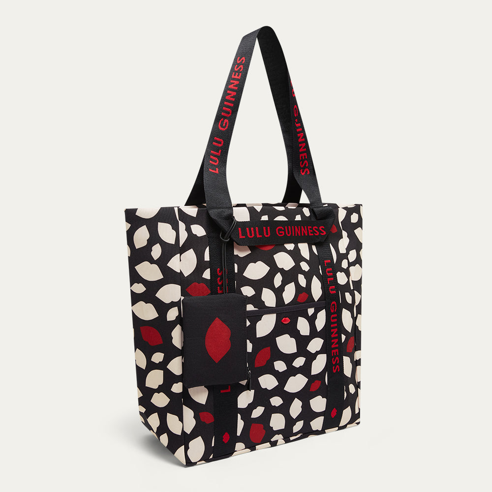 Tote bag with red and white lip flurry print and 'Lulu Guinness' branding with a detachable lip print pouch on a white background