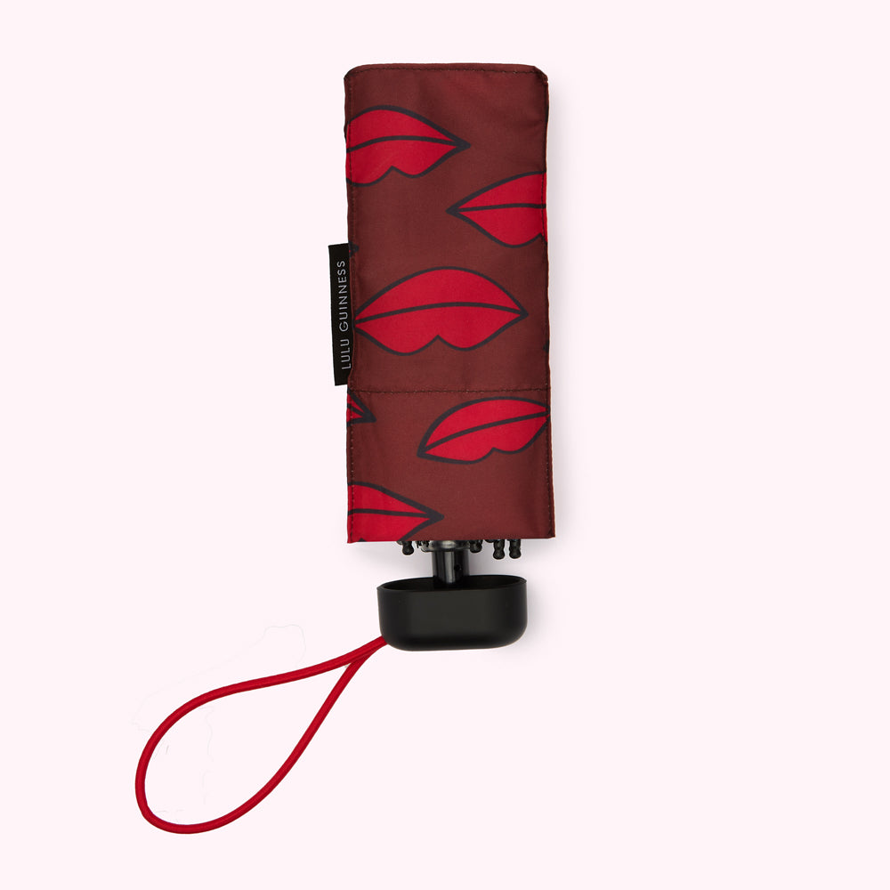 Lulu Guinness red lips mini umbrella, closed, on white background.