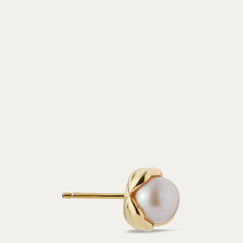 Gold stud earring with a pearl on a light beige background