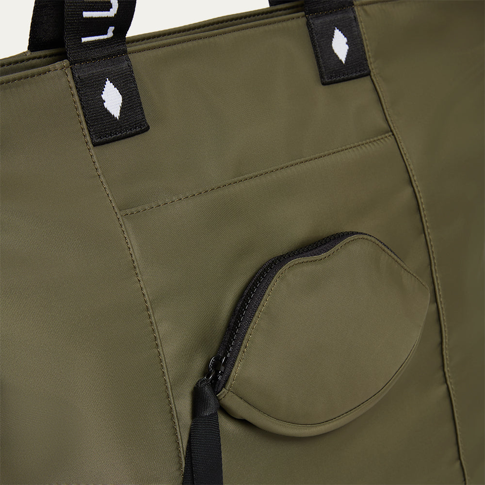 Close-up of a green bag with a lip-shaped pocket and black straps on a white background