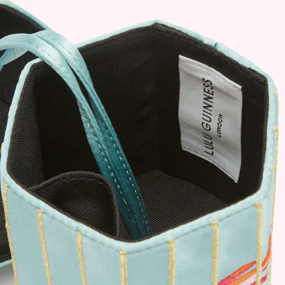 Close-up of a light blue Lulu Guinness box with gold stripes and a teal satin ribbon, the inside shows a black fabric lining and a white label reading "Lulu Guinness London".