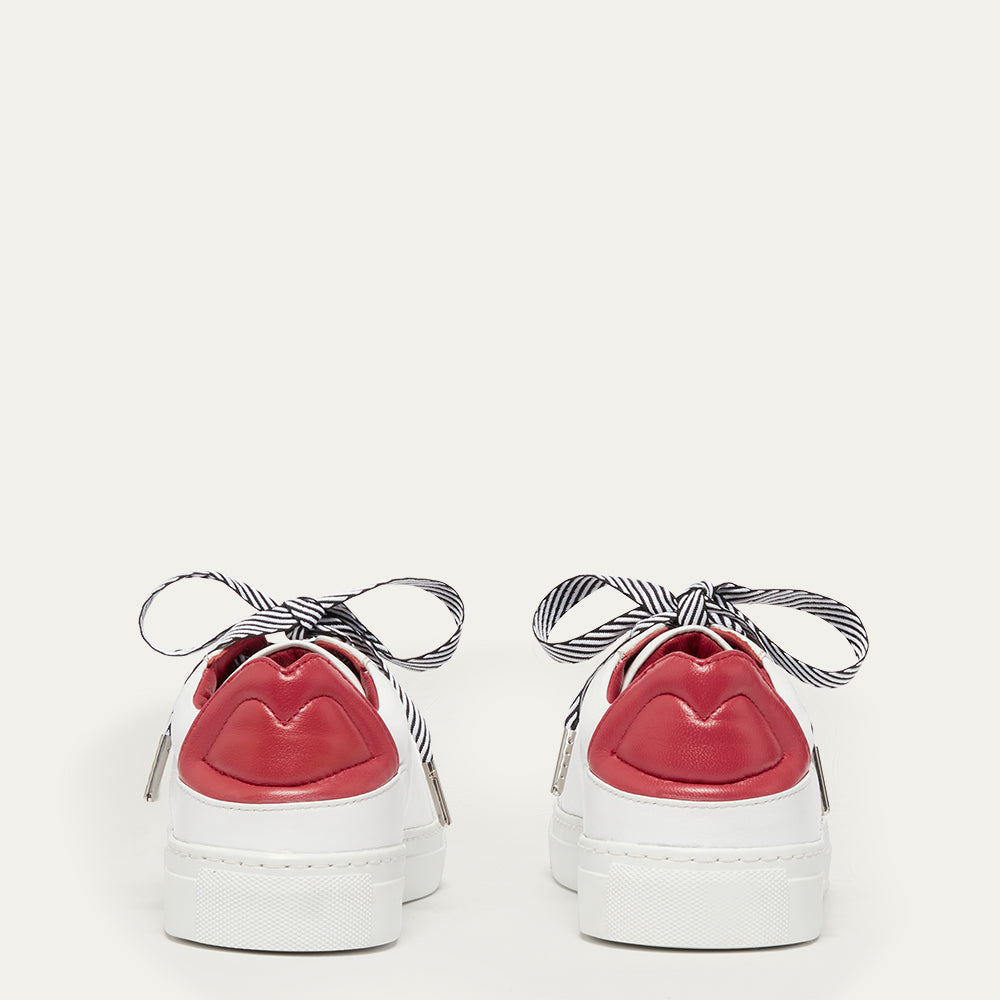 White trainer with red lip details and striped black and white laces on a light gray background