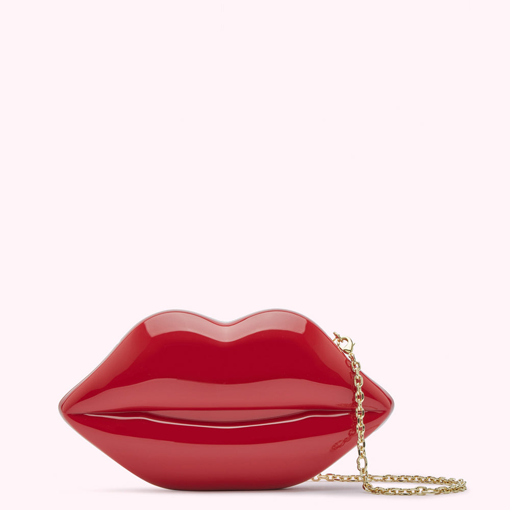 Red lip-shaped clutch with gold chain strap against a white background.
