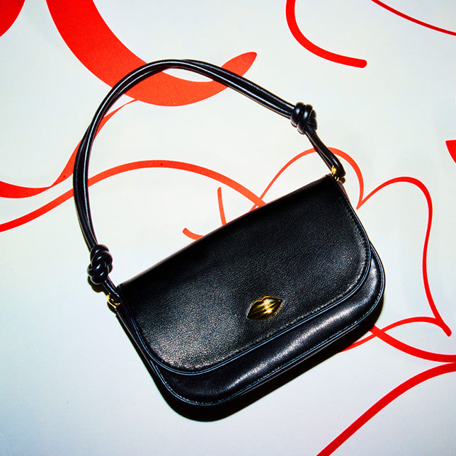 A boxed Lulu Guinness purse with a red phone box embroidered on the black  satin ground and the words 
