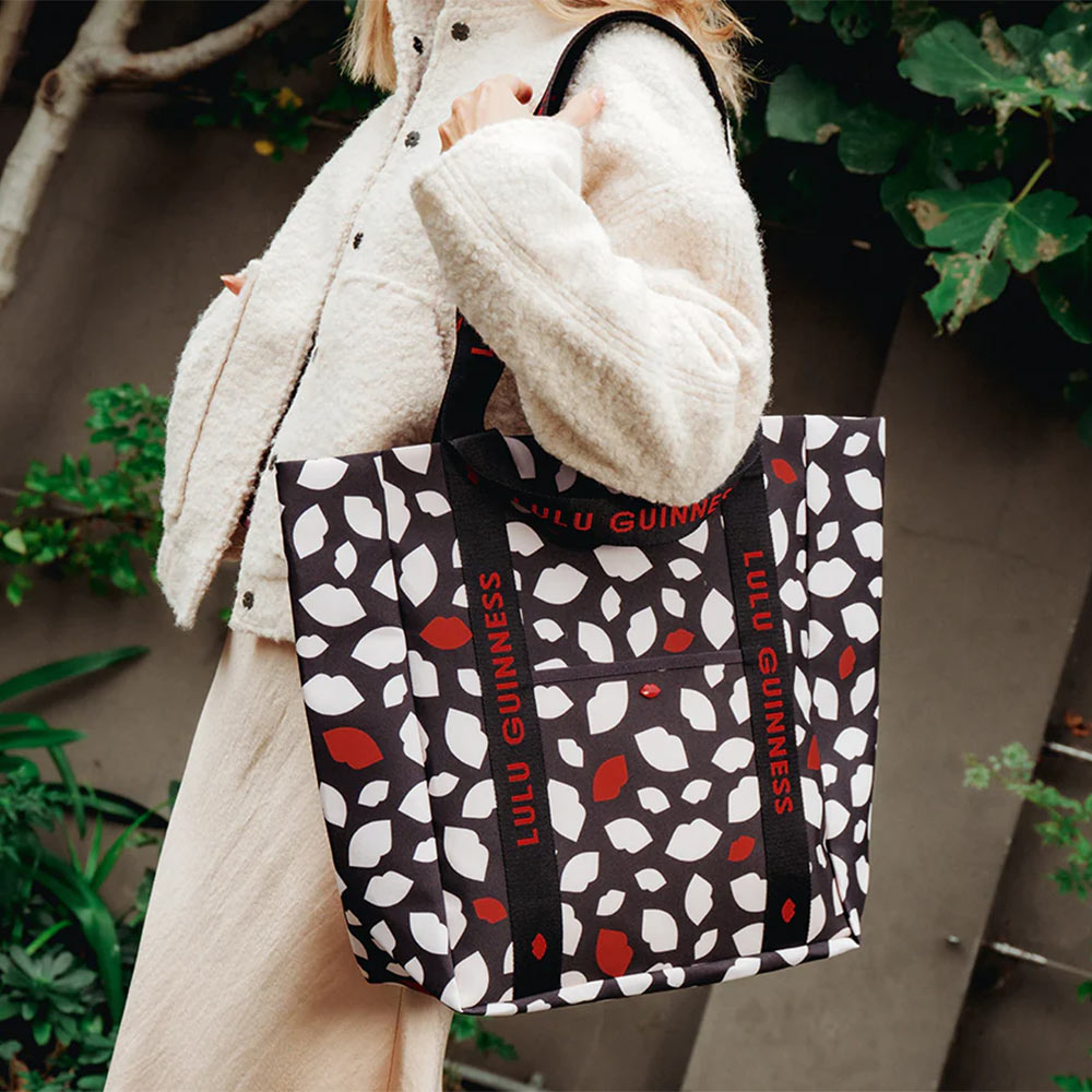 Person holding a Lulu Guinness bag with lip flurry print of red, white and black